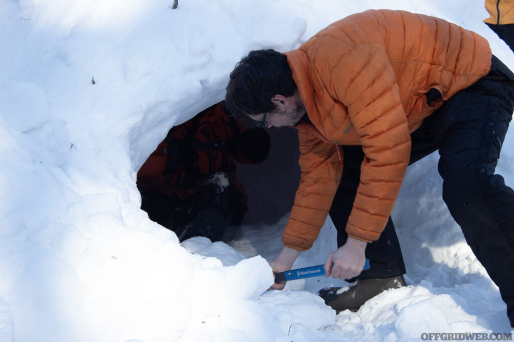 Photo of instructor Jerry Saunders helping students dig out the inside of a quinzee hut.