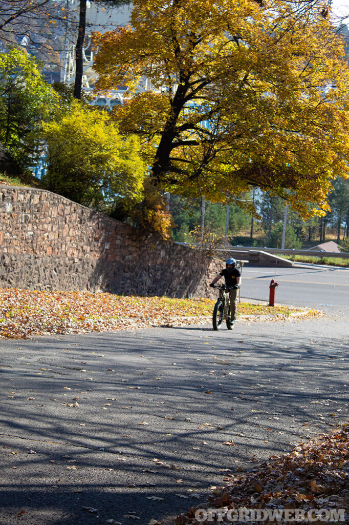 Photo of an adult male riding an eBike up a steep hill.