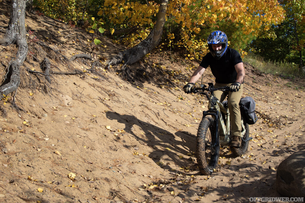 Photo of an adult male riding over sand dunes on a fat-tire eBike.