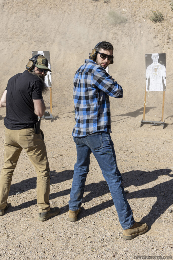 Photo of two men shooting and pistol targets at an outside range.